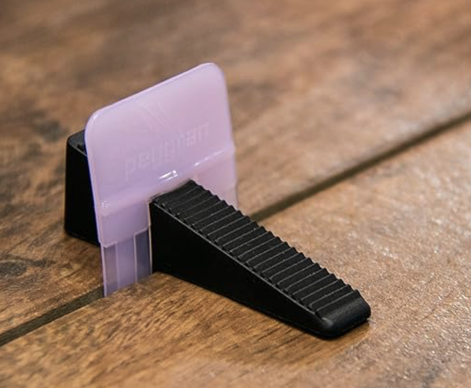 Peygran Classic black wedge inserted into a leveling clip between tiles